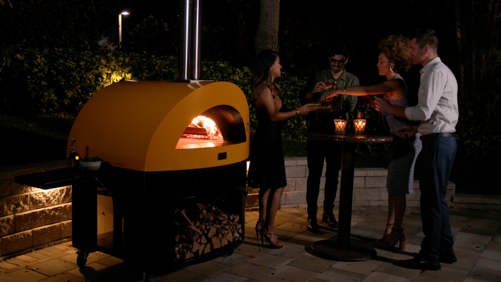 Crowd of people gathered around a pizza oven